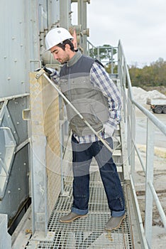 Laborer outside factory working dressed with safety overalls equipment