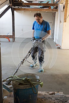 Laborer polishing sand and cement screed floor.