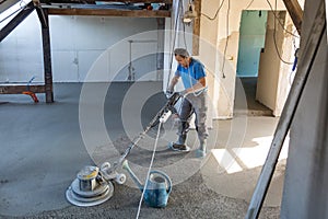 Laborer polishing sand and cement screed floor.