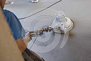 Laborer polishing sand and cement screed floor.