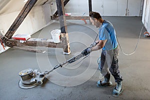 Laborer polishing sand and cement screed floor.