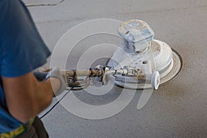 Laborer polishing sand and cement screed floor.