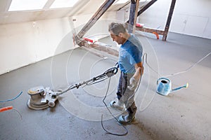 Laborer polishing sand and cement screed floor.