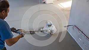 Laborer polishing sand and cement screed floor.