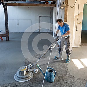 Laborer polishing sand and cement screed floor. photo