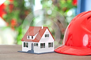 Laborer with red hard hat and small house model