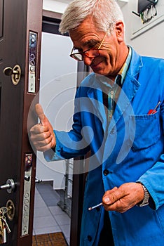 Laborer repairs the door lock in hallway