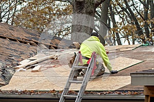 Laborer repairs a roof on an old home