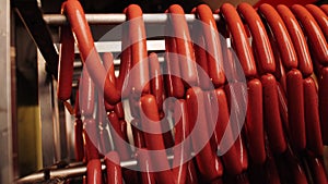 Laborer takes out rack with sausages from oven in workshop