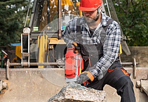 A laborer uses a jackhammer to break up a concrete pavement