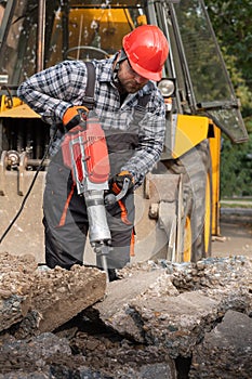 A laborer uses a jackhammer to break up a concrete pavement