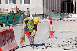 A laborer uses a jackhammer to break up a concrete pavement
