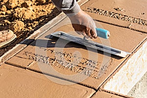 Laborer Using Trowel On Wet Cement Forming Coping Around New Pool