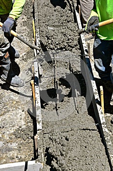 Laborers moving wet concrete on a building project as footings are created.