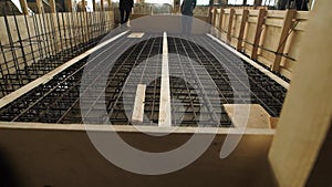 Laborers are standing and walking over reinforcing cage floor slab in a construction site in working day