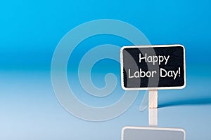 Labour day - May 1st. Day 1 of month, text at little woden tag on blue background with copy space. Spring time