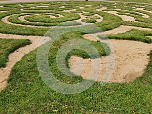 Labyrinth of green grass and sand in the garden.