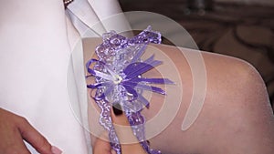 The lace garter is put on the bride`s leg