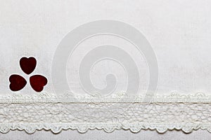 Lace ribbon hearts on white cloth.