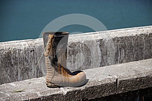 Lace up rubber boot discarded at the sea front