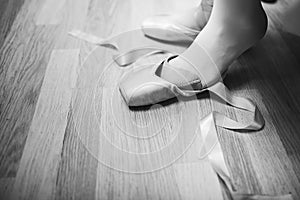 Lacing ballet slippers. Ballerina laces the ribbons of the pointes. BW lifestile photo. close-up of legs