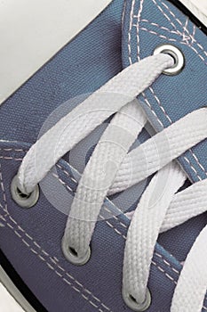 Lacing on a retro sneaker, close-up, on a blue wooden background