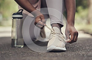 Lacing up to run the race. a woman tying her shoes before working out.