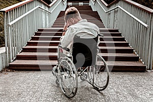 Laconic image of disabled man sitting in front of the stairs