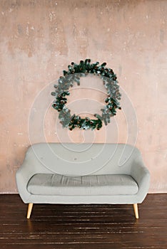 Laconic interior of the living room. Grey sofa and a Christmas wreath on the wall