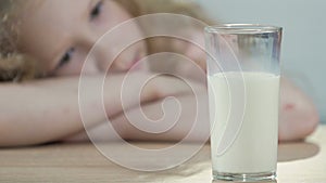 Lactose-intolerant child sadly looking at glass of fresh white milk, nutrition