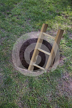 Ladder coming out of a dirt hole in the ground