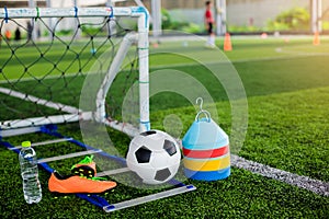 Ladder drills, goal, soccer ball, marker cones, sports shoes and bottle water on green artificial turf