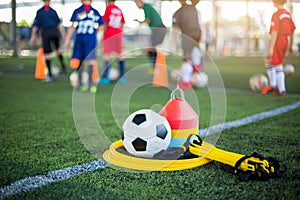 Ladder drills, soccer ball and marker cones on green artificial turf
