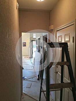Ladder in hallway with sheetrock work in progressin residential home