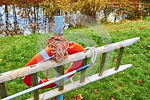 Ladder and lifebuoy at the edge of a lake in a park