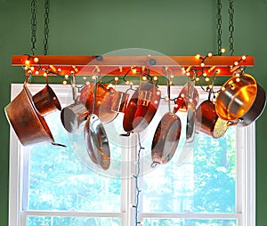 Ladder serving as a pot rack with copper pots hanging from its rungs