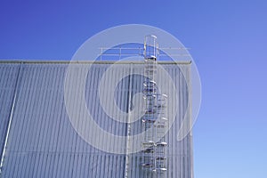 Ladder to the roof of a tall industrial building on blue sky background