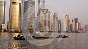 Laden barge with crushed stone down the river Huangpu against the background of glass skyscrapers of the center of