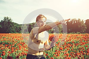 Ladies` man. muscular man in field of red poppy seed