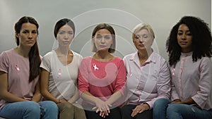 Ladies with pink ribbons looking in camera, moral support breast cancer patients