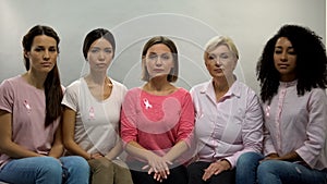 Ladies with pink ribbons looking in camera, moral support breast cancer patients