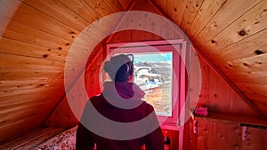 Ladinger Spitz - Rear view on woman looking outside the window from cozy wooden alpine hut. photo