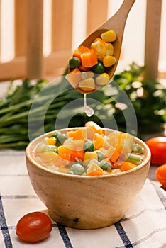 Ladle of steamed freshly harvested young vegetables including cr