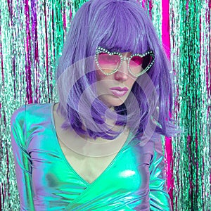 Lady 80s fashion in stylish holographic party look and purple hairs. Tinsel installation. New year`s clubbing concept. Merry