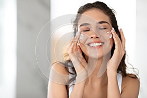 Lady Applying Facial Cream On Cheeks With Eyes Closed Indoor