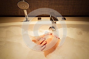 Lady in bathtub with full bubble cleaning her leg in sexy mood photo