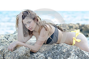 Lady in bikini, lying front on sea rocks