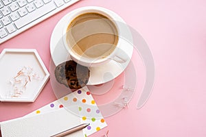 Lady blogger's home workplace, cup of coffee and laptop keyboard on pink tabletop