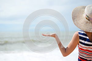 Lady in broadbrim hat facing sun standing on sandy