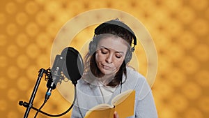 Lady browsing pages, doing voiceover reading of book to produce audiobook